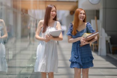 Genç Asyalı kadınlar, dersten sonra üniversite binasında yürümeyi seviyorlar.