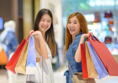 young happy women looking goods staffs items with joyful in shopping mall center, buying and shopping consumerism with many bags holding in both hands clipart