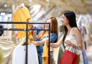 Genç ve mutlu kadınlar alışveriş merkezinde neşeli eşyalar arıyor, alışveriş ve alışveriş tüketiciliği ellerinde bir sürü torbayla.