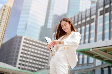 Şehir caddesinde iş ile meşgul çalışan bir kadın, Acelesi kontrol ev çalışma süresi, şehir ofis binasında toplantı için zaman acele