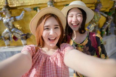 Selfie çeken genç turist kadınlar, Tayland 'ın Bangkok, Zümrüt Buddha Tapınağı, Wat Phra Kaew, Bangkok Kraliyet Sarayı popüler turizm merkezi, Bangkok' taki saray tapınağında seyahatin keyfini çıkarıyorlar.