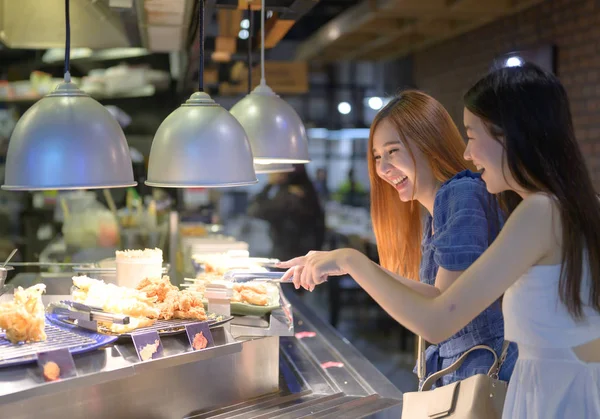 women exciting to having meals in food court of the shopping mall
