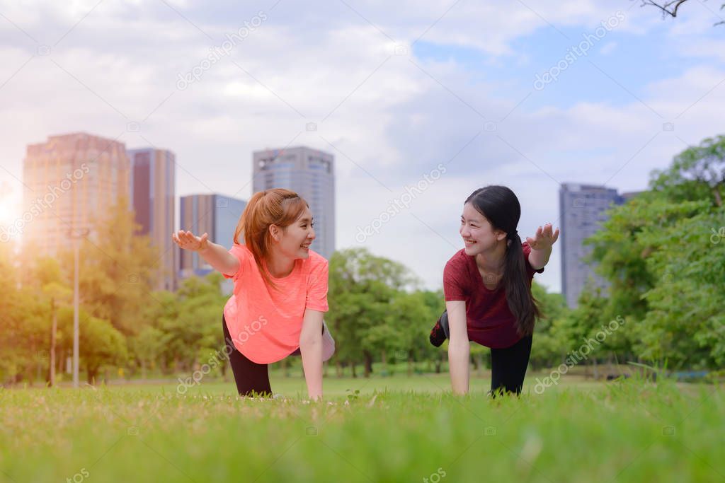 young asian women doing gesture of yoga training in city public park  together