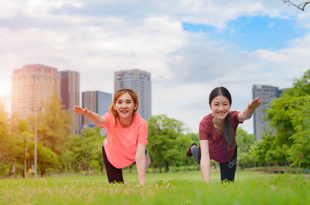 young asian women doing gesture of exercise yoga training in city public park