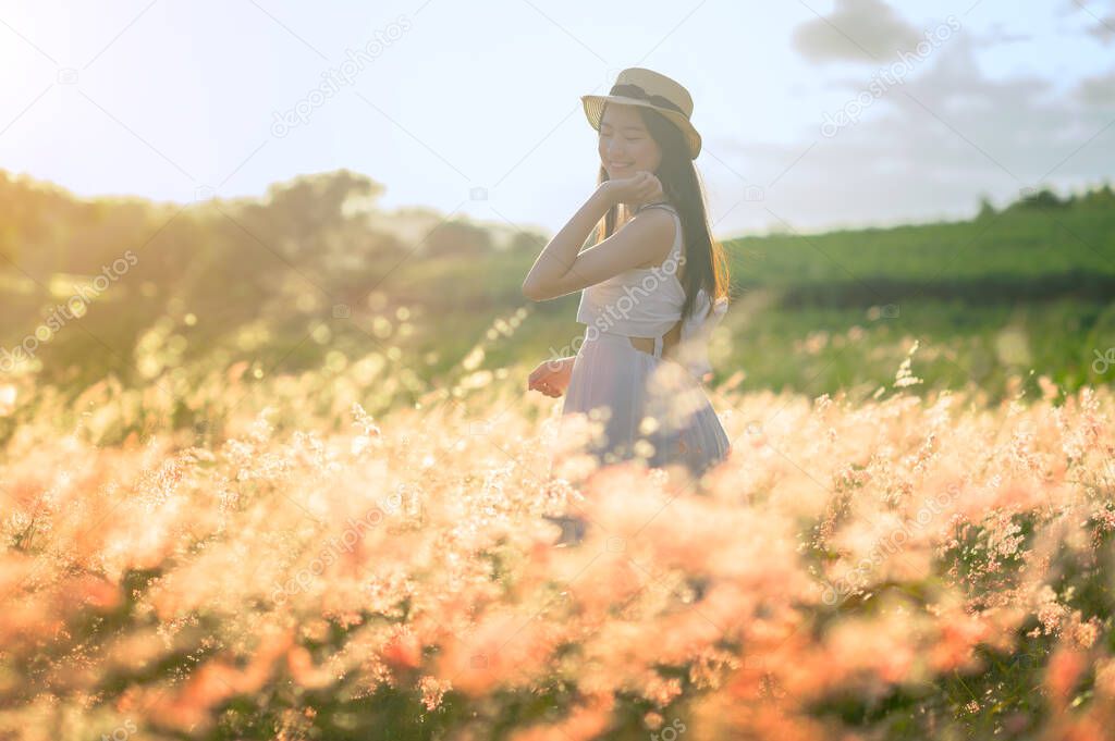 young woman walks feel freedom in the light of warm sun, bloom of wild flower in meadow, enjoyment and peaceful in the field of meadow