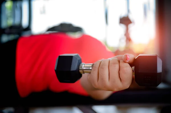 hand of fat plump woman holding weight Dumbbell in gymnasium, workout reduce body weight