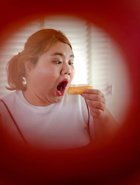 plump fatty woman hunger eating junk foof sweet donut creamy at high calories sweet cycle in forgroun