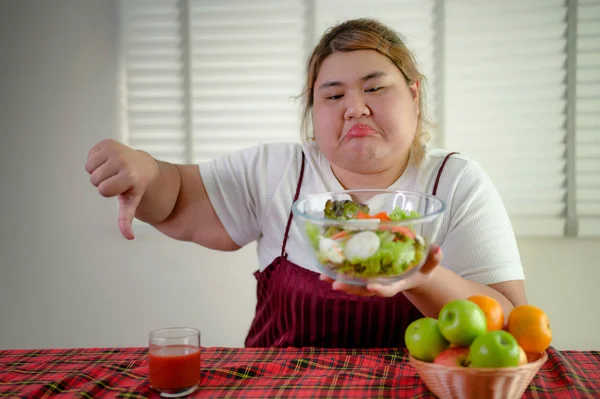 plump fatty woman anti and refused to eat salad vegetable and fruit on table, do not wants to eat salad food, against vegetable green salad, un-preferable fruit vegetable salad