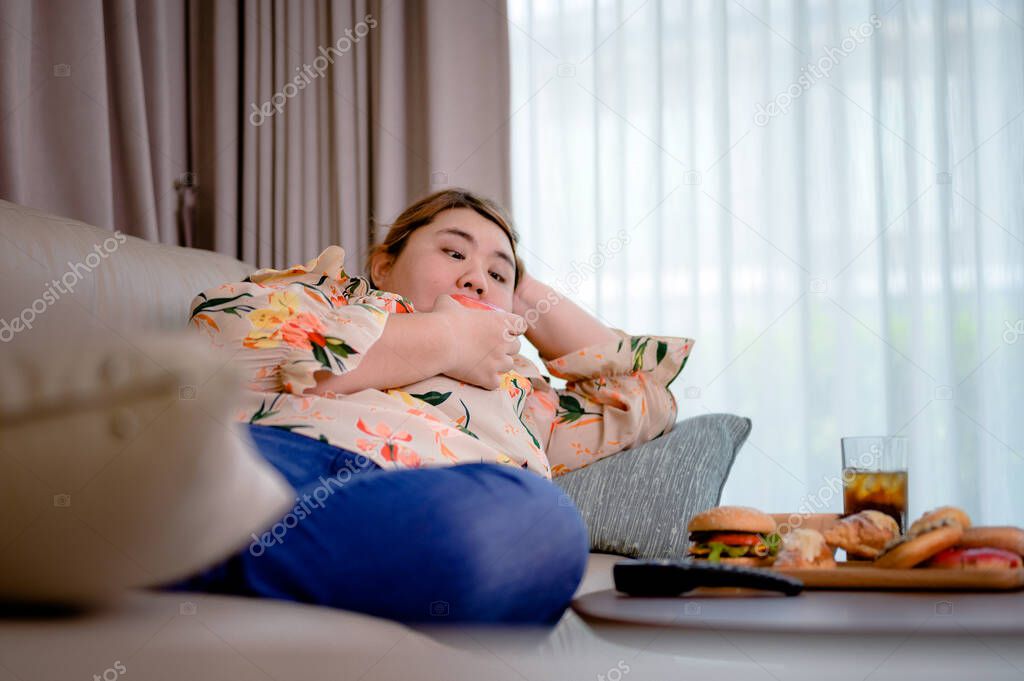 fat plump woman enjoy eating junk food in home while watching TV relaxation