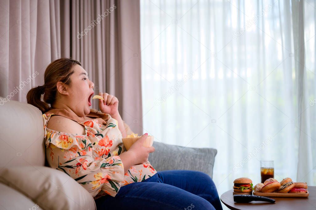 fat plump woman enjoy eating junk food in home while watching TV relaxation