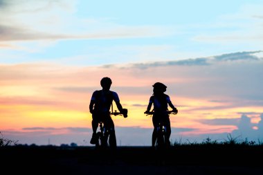 couple lover biker cyclist riding enjoyment to the field of meadow lake at sunset, adventure bicycle wild and journey activity
