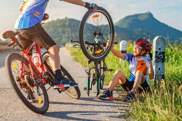 Счастлива, что женщине помогли другой рукой байкер для ремонта переднего колеса, помощник друг на друга во время неприятностей по дороге ездит на велосипеде
