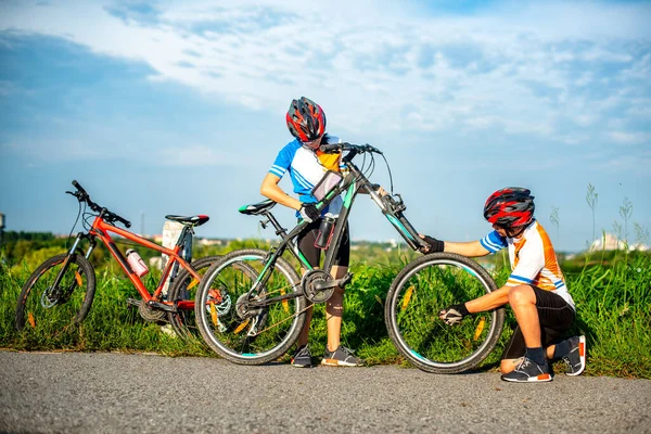 woman cyclist has a problem during the way needs wheel tire to repairing, helping by bicycle mate takes wheel fixing, assist on each other trouble