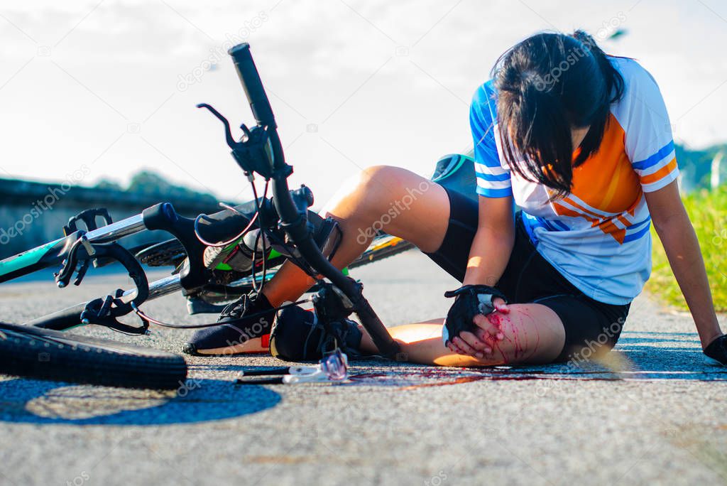 woman bicycling in hurt and injuried of leg after accident clashed, with wound and bleeding of blood flow on the surface of street road