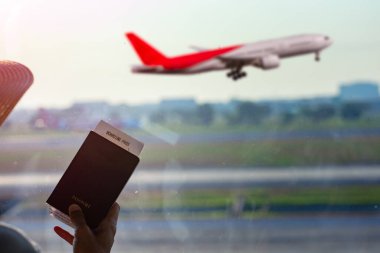 Pasaportu ve uçuş kartı olan bir kadın havaalanında bekliyor. Bir sonraki seyahat programı için bekliyor. Gidişin gecikmesi. 
