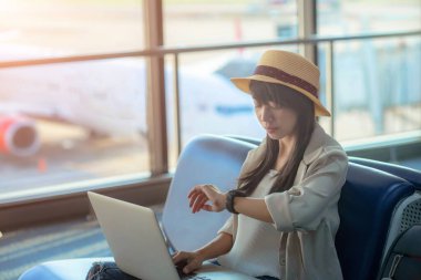 Yolcu kadın, uçağın zaman çizelgesinde gecikme olmasından endişe ediyor. Havaalanı terminalinin ulaşım bölgesinde uçak kalkana kadar sıkıcı kalın.