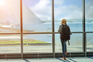 Havaalanının ulaşım alanında pasaportu olan kadın yolcu, bir sonraki seyahat programı için beklemede kalın, varış saatini geciktirin, uçuş kartını kontrol edin.