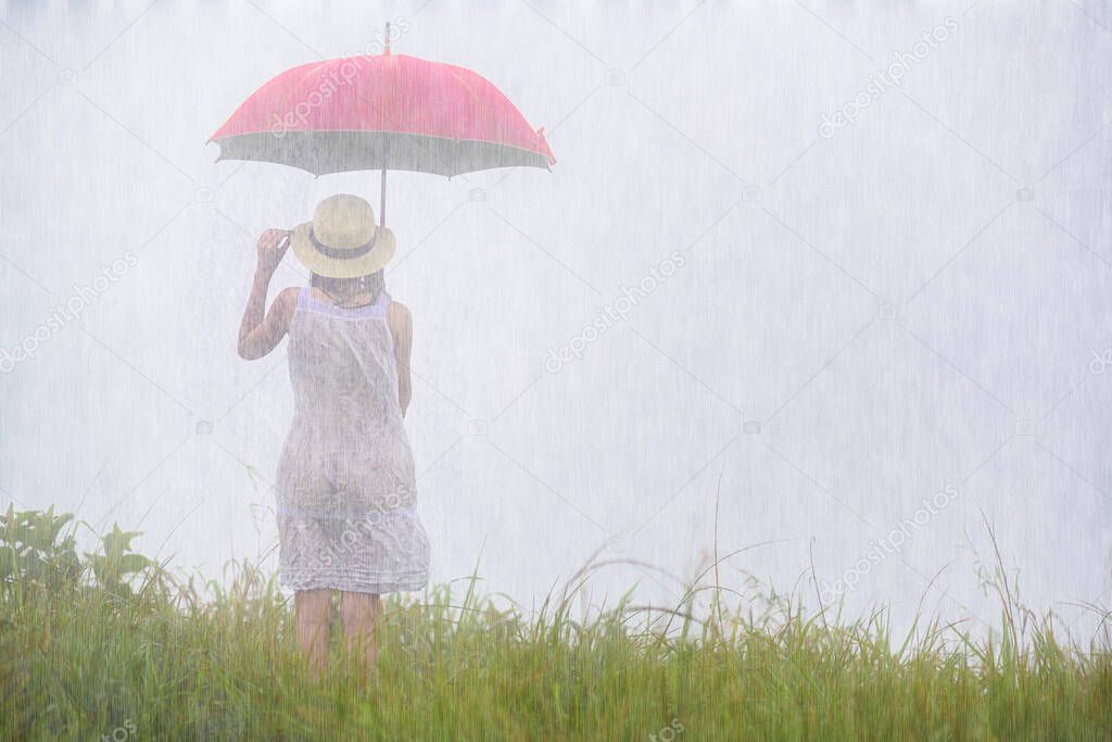 woman holding red umbrella standing in the raining at meadow field, stand alone emotion in the rain storm