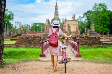 Kadın turist, Tayland 'ın tarihi parkını görmek için yerel bisiklete binmeyi seviyor. Gezinin harika mekanını keşfetmek heyecan verici.