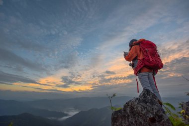 Sırt çantalı kadın turist dağlarda doğanın tadını çıkarıyor, vahşi doğada tek başına gezen bir kadın dağın zirvesinde yürüyüş yapıyor.