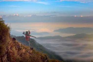 Dağın zirvesinin manzarası. Altında sis ve sis var. Fotoğrafçı orman boyunca dağ yürüyüşü yapıyor.