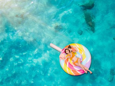 Kadın bikinisi mobil tabletle oynamaktan, deniz suyunda yanıcı tüpte yatmaktan, yaz tatillerinde uzun tatillerde denizde rahat hissetmekten zevk alır.