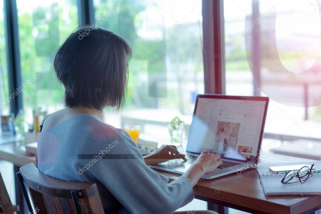 Thoughtful concept. Woman working on a computer at a cafe while gazing through the window glass. - Image