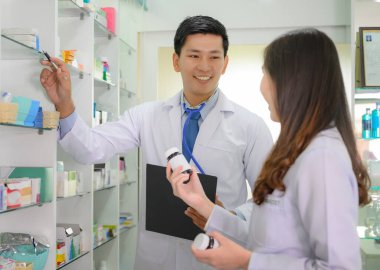 Envanter listesini kontrol etmekle görevli doktor ve kadın eczacı, eczanede birlikte çalışıyor.