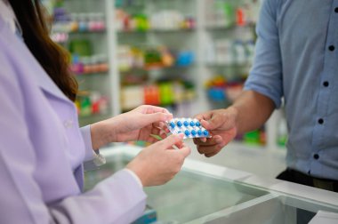 hands of selling pharmacist and man customers buyin medicine in drug store, handover pills of medicine from hand to another hand charge