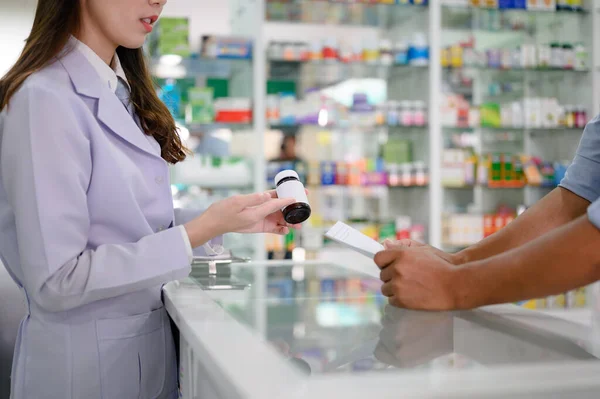 bottle of medicine tablets or pills in hand of woman pharmacist in explanation apply to man customer, discussion in property of medicine how to apply to the outpatient