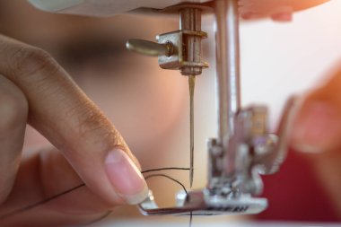 Kanalizasyonun ya da ev kadınının eli dikiş makinesinin iğnesine iplik sokmaya çalışır. Küçük terzilik işlerinde zorlanan yaşlı kadın gözü.   