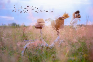 Çayırlarda dikilen eski bir bisiklet bekleyen çift sevgili sevgililer günü balayı vesilesiyle yumuşuyor ve çıldırıyor.