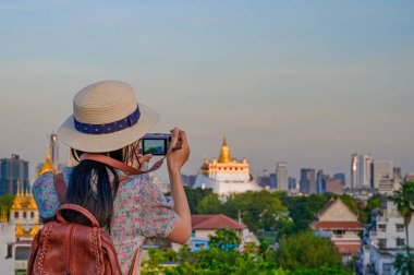 Turist iş başındayken ve heyecan içindeyken Bangkok Tayland 'ın popüler turistik mekanı olan Wat Saket' in altın tapınağıyla fotoğraf çekiyor.