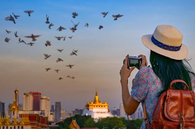 Turist iş başındayken ve heyecan içindeyken Bangkok Tayland 'ın popüler turist merkezi olan Wat Saket' in altın tapınağıyla fotoğraf çekiyor.