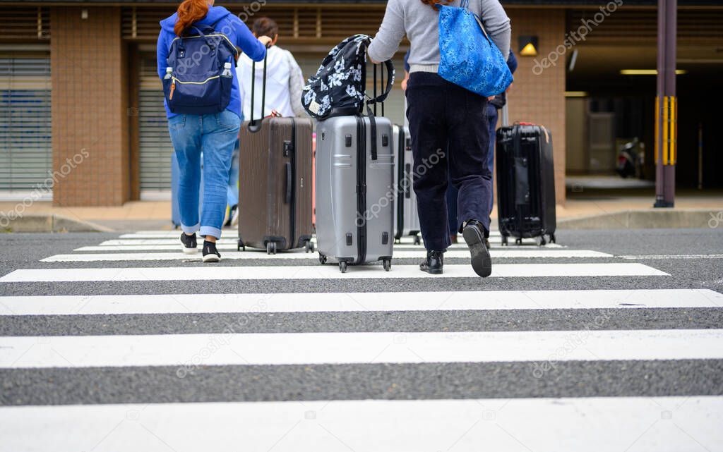 luggages belongings of tourist trvellers walks crossing the city street road in rush hours