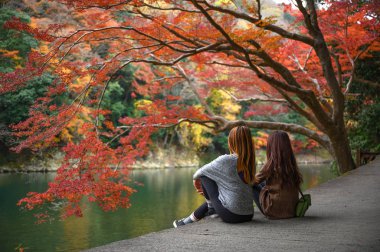 Kadın turist sonbahar mevsimi değişiminde nehir manzarasına bakar, Japonya 'yı ziyaret eder ve seyahat eder. 