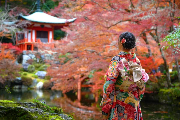 Geleneksel kimono tarzı retro şemsiyeli kadın, sonbaharda köyün bahçesinin ortasında oturuyor, Japonya 'ya geliyor ve spor müsabakalarını ziyaret ediyor.