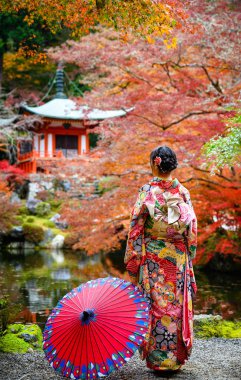 Geleneksel kimono tarzı retro şemsiyeli kadın, sonbaharda köyün bahçesinin ortasında tek başına duruyor, Japonya 'ya geliyor spor müsabakalarında seyahat ediyor ve ziyaret ediyor.