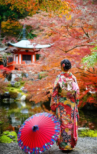 Geleneksel kimono tarzı retro şemsiyeli kadın, sonbaharda köyün bahçesinin ortasında tek başına duruyor, Japonya 'ya geliyor spor müsabakalarında seyahat ediyor ve ziyaret ediyor.