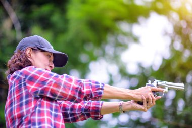 old woman wearing ear plug hearing protection with hand holding a Short magazine gun in practice of arm and weapon martial art for woman