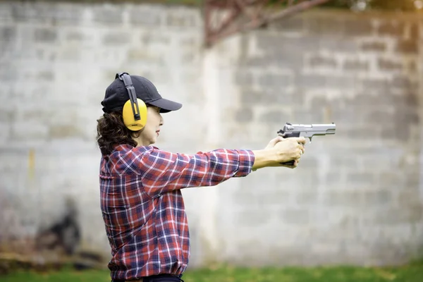 old woman wearing ear plug hearing protection with hand holding a Short magazine gun in practice of arm and weapon martial art for woman