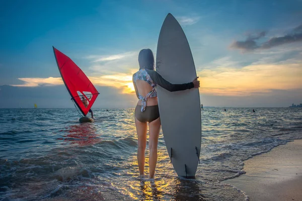 身材苗条的女人要去玩冲浪板练习 站在海浪的浪尖边 身后是风浪冲浪者 — 图库照片