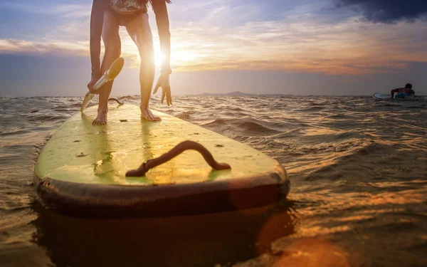 年轻女子的动作就是要站在海里的冲浪板上 在冲浪板上对初学者进行冲浪技巧训练 — 图库照片