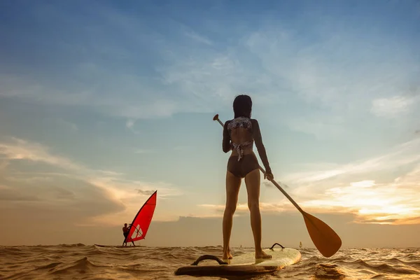 身材苗条的年轻女子站在冲浪板上划桨入海 享受暑假冲浪的乐趣 — 图库照片