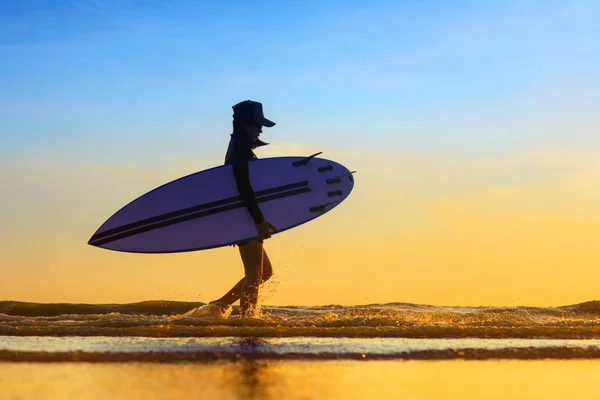 在海浪边行走的女人的侧影 在通过时的水花飞溅 在夕阳西下在海里冲浪后的归国状态 — 图库照片