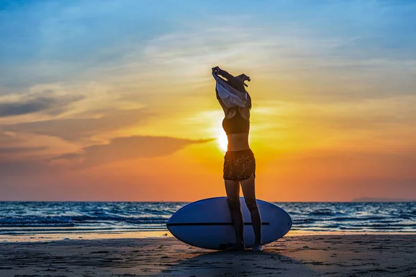 파도타기를 여자들 바다에서 운동을 연습하기 스포츠 셔츠를 벗는다 — 스톡 사진