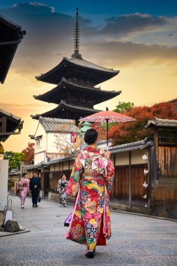 Geleneksel kimono tarzı retro şemsiyeli kadın, sonbaharda bahçe köyünün orta parkında yürüyor, Japonya 'ya geliyor ve spor müsabakalarını ziyaret ediyor.