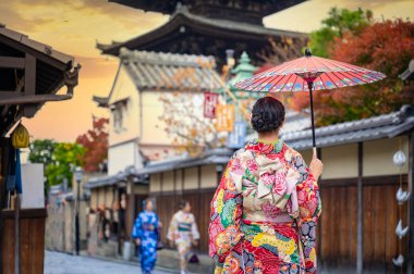 Geleneksel kimono tarzı retro şemsiyeli kadın, sonbaharda bahçe köyünün orta parkında yürüyor, Japonya 'ya geliyor ve spor müsabakalarını ziyaret ediyor.