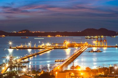 Deniz limanı terminali gün batımında dünya çapında lojistik hizmetler için yükleme ve boşaltma kargo sevkiyatı yapıyor.