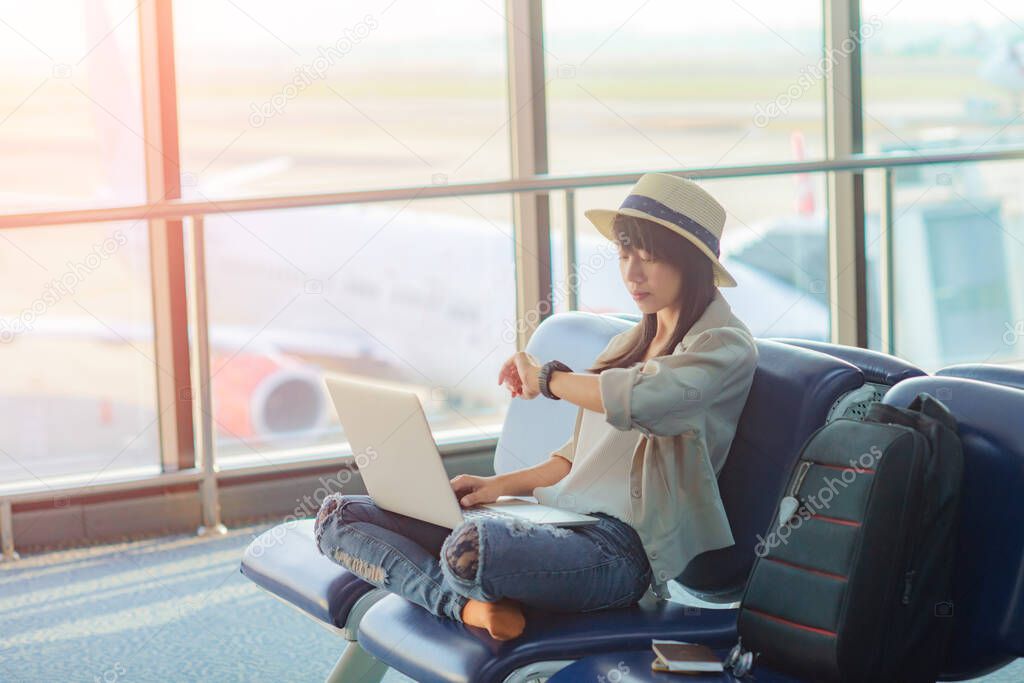 woman traveler passenger in worry of the time schedule delay of the aircraft, stay boring in the transit area of air port terminal waiting for boarding airplane